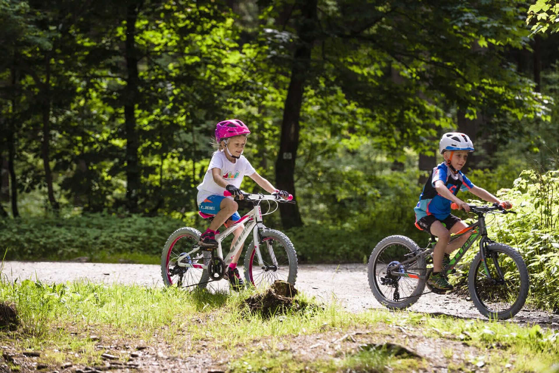 Two kids on small kids bikes in a park